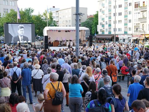 Menschen stehen vor einer Bühne und einer LED-Leinwand