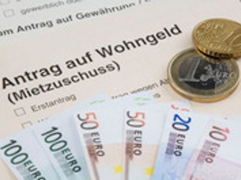 Scheine und Münzgeld liegen auf einem Antrag auf Wohngeld (Mietzuschuss)