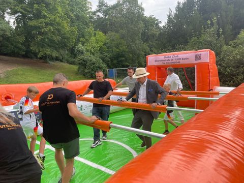 Ein lebensgroßer Kicker ist zu sehen, wo Kinder und Erwachsene gemeinsam spielen.