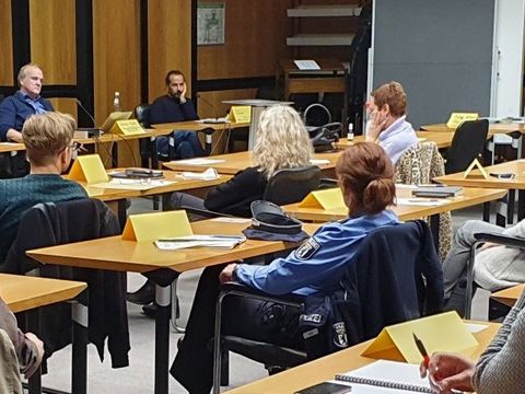 Mehrere Menschen sitzen mit Abstand an Tischen