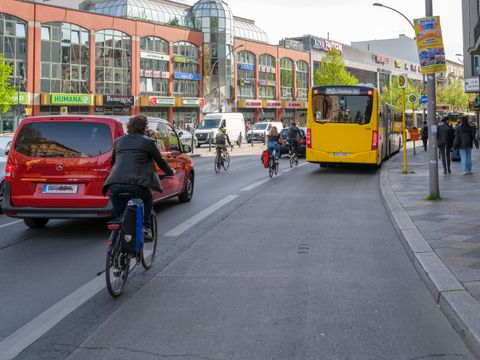 Fahrradfahrer an der Haupstraße zwischen Autos und Bus