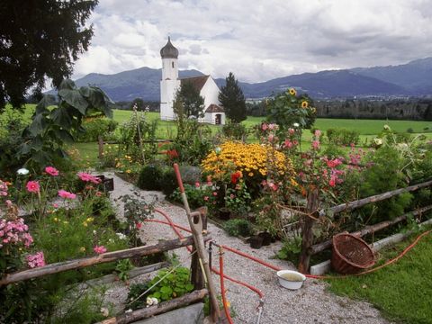 Grüner Hügel mit Dorfkirche und Blumenbeeten