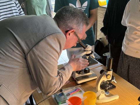 Bezirksbürgermeister Igel steht an einem Mikroskop im Freilandlabor Kaniswall