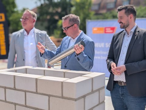 Zeitkapsel wird von Bezirksbürgermeister Igel im Grundstein versenkt