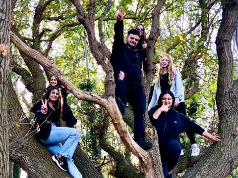Jugendliche sitzen mit einem Mitarbeiter im Baum und posieren
