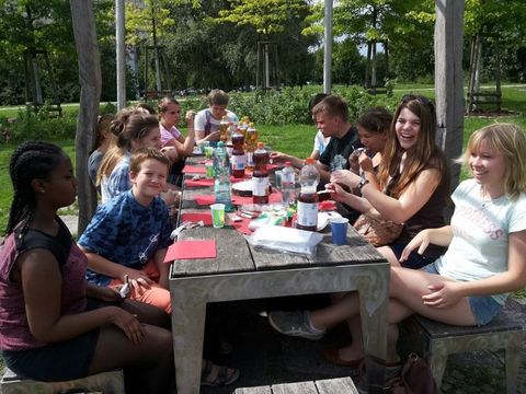 Jugendliche sitzen in der Natur am Frühstückstisch