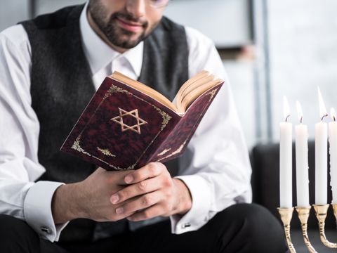 Ausgeschnittene Ansicht eines jüdischen Mannes, der in seiner Wohnung Tanach