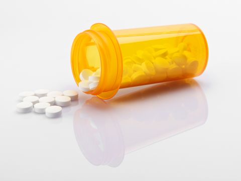 Pillen und orange Dose auf weißem Grund