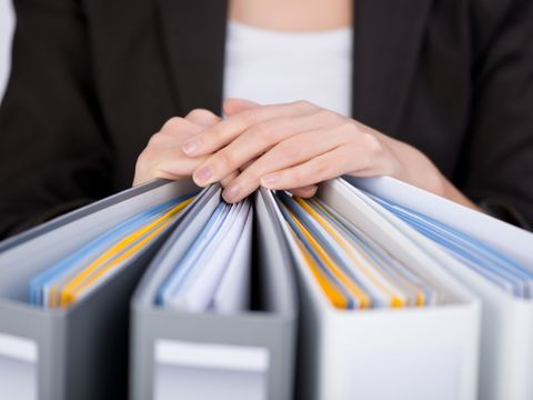Frauenhände auf vier Aktenordnern