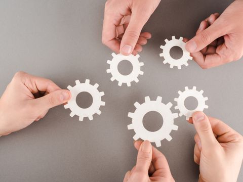 Abgeschnittene Ansicht von Menschen mit weißen Zahnrädern auf grauem Hintergrund