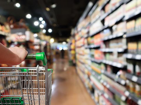 Frau mit Einkaufswagen im Supermarkt mit abstrakter Unschärfe im Hintergrund