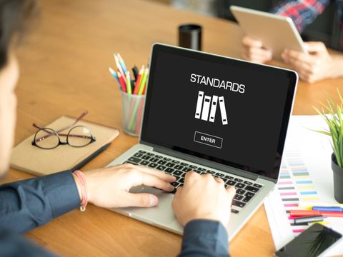 Hände am Laptop, auf dem Bildschirm stehen die Worte Standards und Enter