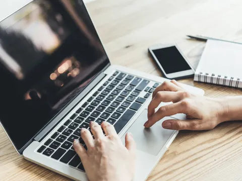 Hände berühren die Tastatur eines Laptops