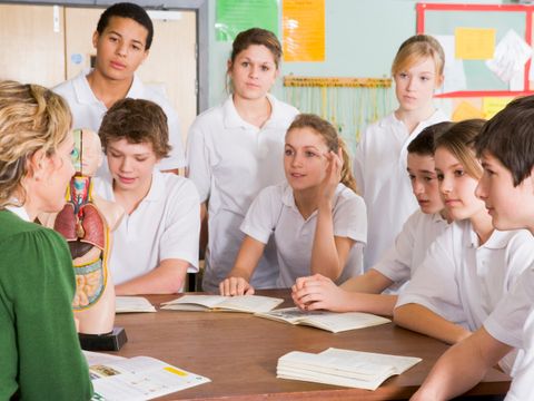Schüler sitzen mit Lehrerin am Tisch