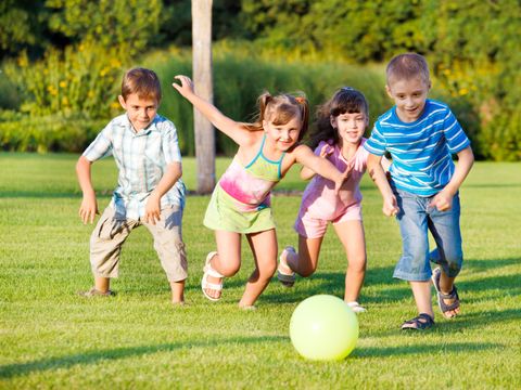 Jungen und Mädchen laufen hinter Ball her