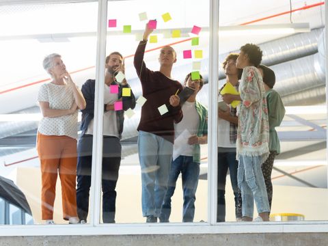 Menschen verschiedenen Alters brainstormen mit Klebezetteln