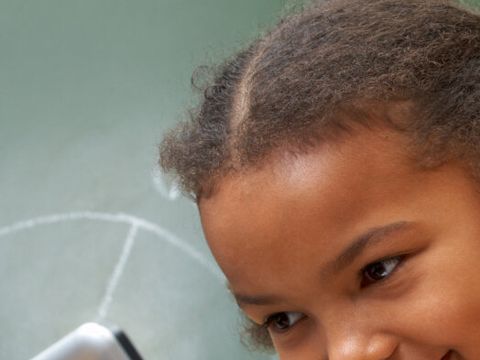 zwei Kinder vor einem Laptop mit Tafel im Hintergrund