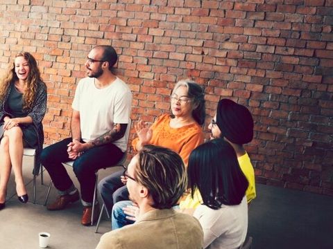 verschiedene Menschen sitzen im Stuhlkreis zusammen
