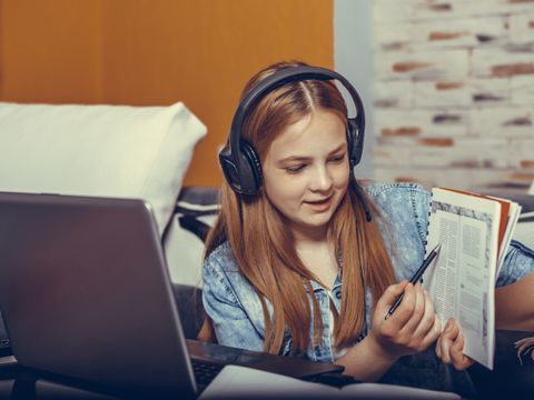 Kind mit Headset, Laptop und Buch