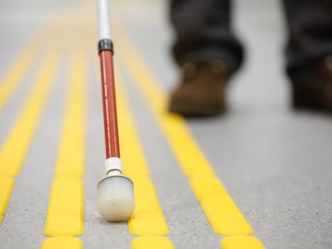 Blindenstock auf dem Bodenleitsystem eines Bahnsteigs