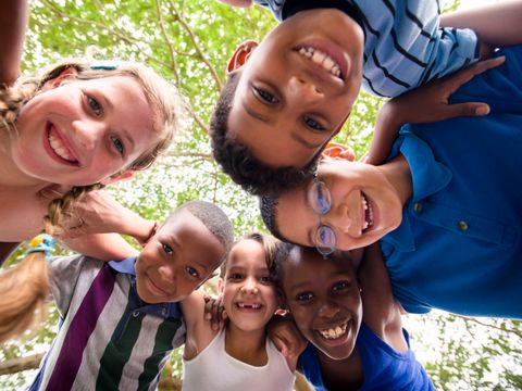 Kinder umarmen sich im Kreis um die Kamera und lächeln