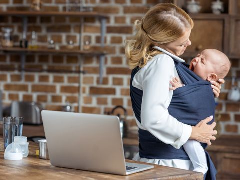 Mutter am Handy hält Kind im Arm