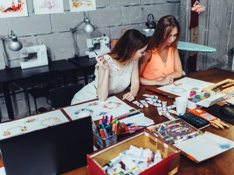 zwei Studentinnen vor Grafikentwürfen am Schreibtisch