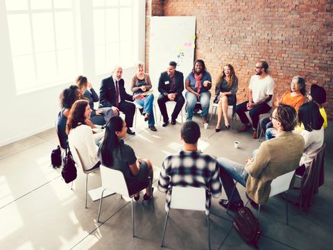 verschiedene Menschen sitzen im Stuhlkreis zusammen