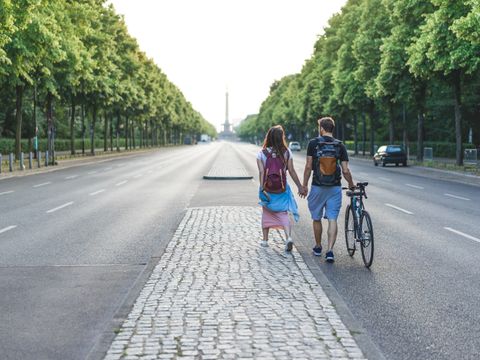 ein Pärchen mit Fahrrad läuft auf der leeren Straße des 17. Juni