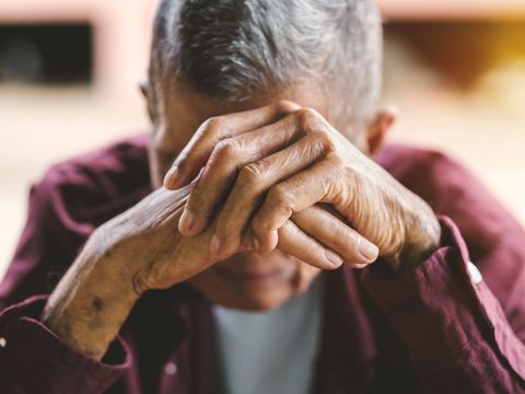 Seniorin hält die Hände vor dem Gesicht
