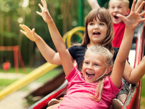 Glückliche Kinder spielen auf Rutsche