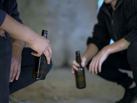 zwei Männer hockend, trinken Alkohol