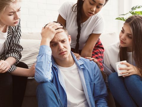 Junge Leute trösten ihren aufgebrachten Freund, diskutieren Probleme zu Hause