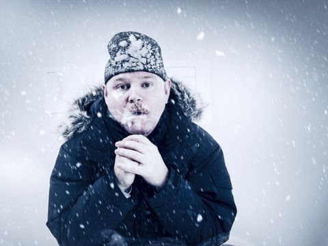 Mann mit Winterjacke und Mütze friert