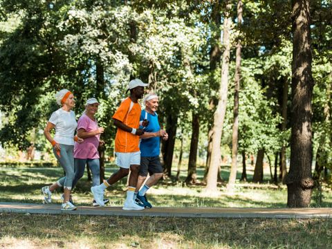 Fröhliche, multikulturelle und ältere Männer und Frauen, die im Park laufen