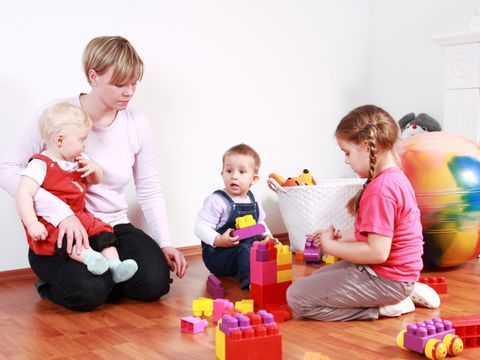 Kindergärtnerin und 3 Kinder spielen