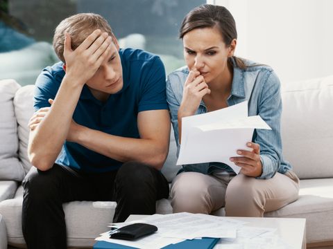 junges Paar schaut bedrückt auf ein Blatt Papier