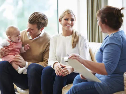 Gesundheitsbesucher sprechen mit jungem Baby mit der Familie