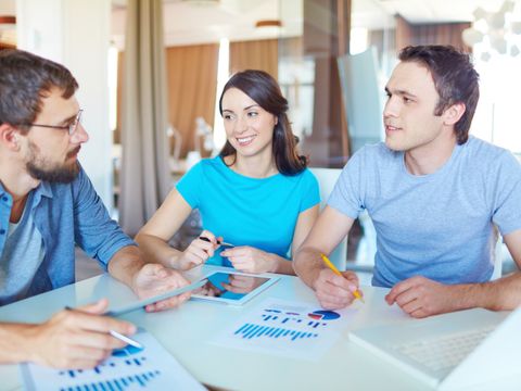Drei Personen sitzen am Tisch und diskutieren