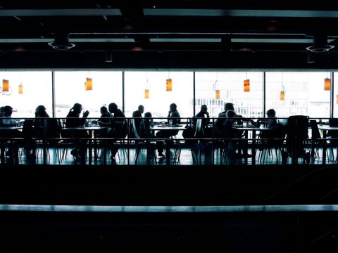 Menschen in eimen Tagescafe sitzend an Tischen.