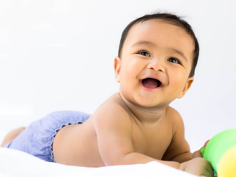 Baby liegt auf dem Bauch und lächelt