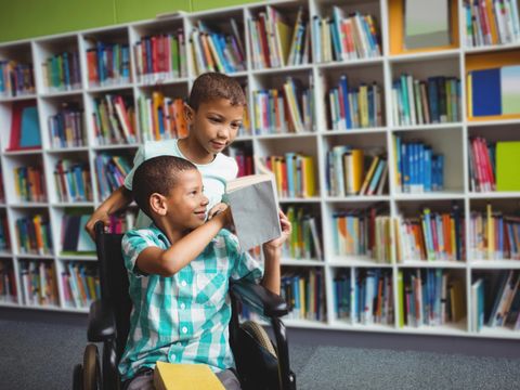Kleine Jungen lesen ein Buch in der Bibliothek
