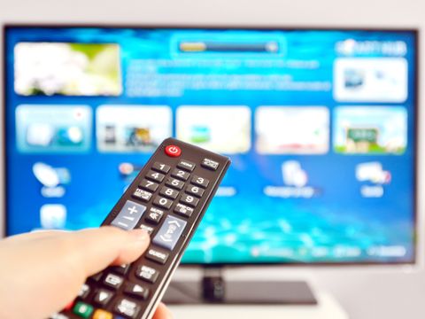 Hand hält Fernbedienung vor SmartTV