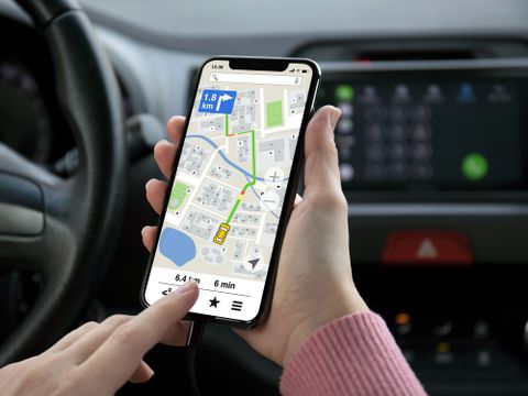 Eine Frauenhand hält ein Telefon mit einer App Navigationskarte auf dem Bildschirm