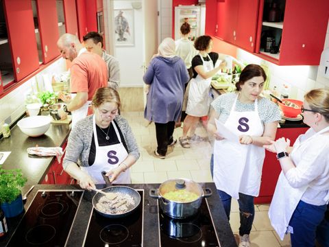 Acht Menschen kochen in einer Küche