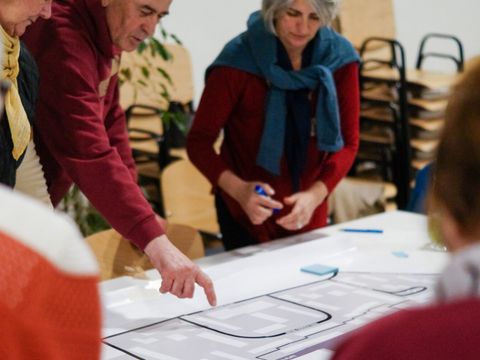 Personen stehen hinter einem Tisch, darauf liegt ein Plan
