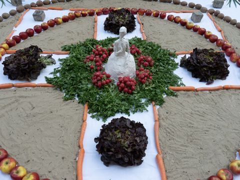 Ein Mandala gelegt auch Äpfeln, Roter Bete, Salatköpfen und weiterem Gemüse und Obst