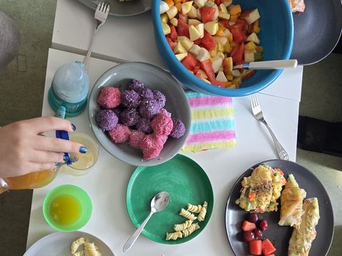 Tisch mit Tellern und Schüsseln gefüllt mit bunten Lebensmitteln wie Obstspießen und Obstsalat