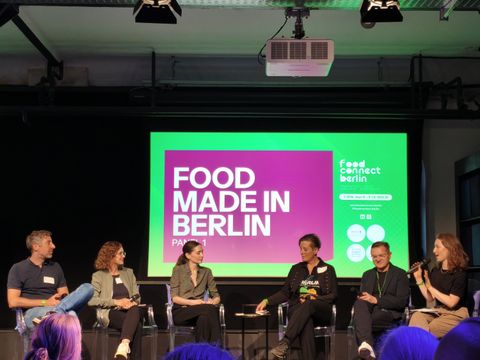 Sechs Leute sitzen auf einer Bühne, im Hintergrund ist eine Präsentation eingeblendet mit dem Schriftzug "Food Made in Berlin"