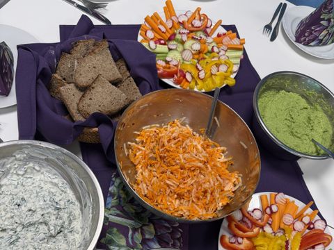 Schüsseln mit Salaten, Dipps und Gemüse und Brot auf einem Tisch